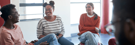 A group of people sit together in a circle, talking and laughing.