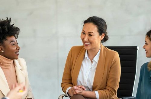 Leading with Emotional Intelligence in Times of Uncertainty Group of professionals in a casual business meeting, smiling and engaged in discussion in a modern office.