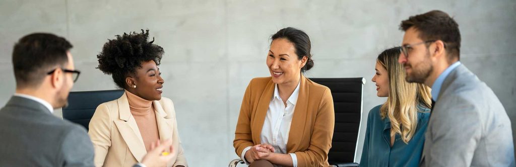 Leading with Emotional Intelligence in Times of Uncertainty Group of professionals in a casual business meeting, smiling and engaged in discussion in a modern office.