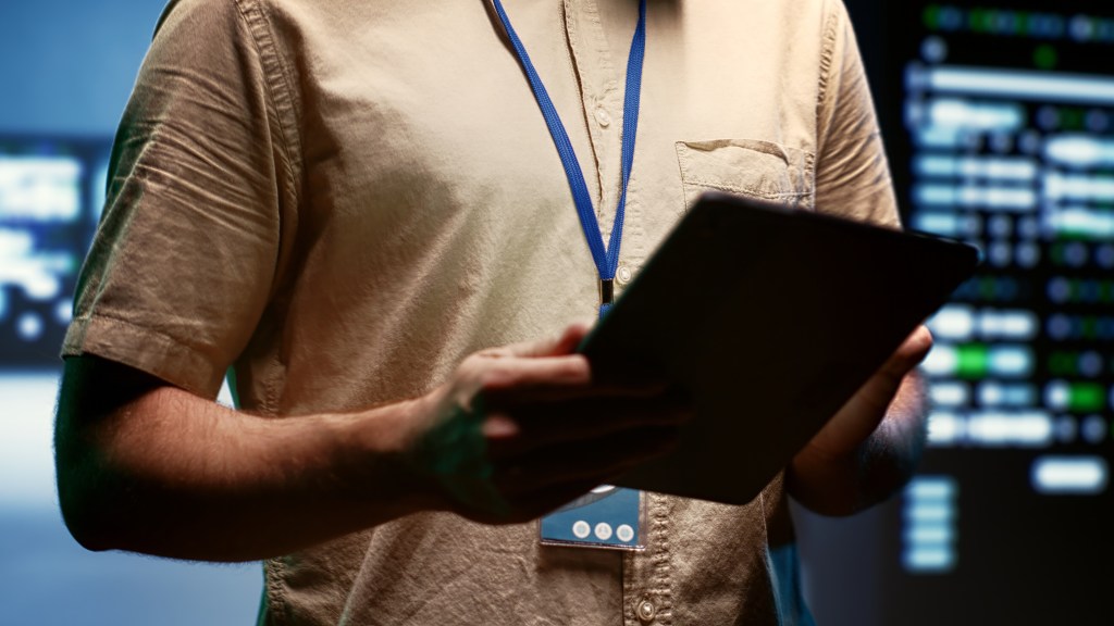 Engineer doing annual maintenance, helping extend data center hardware life span and avoiding downtime. Expert monitoring server infrastructure components using tablet, close up.