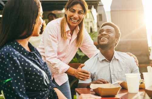 Three adults smiling and interacting in a friendly, supportive outdoor setting